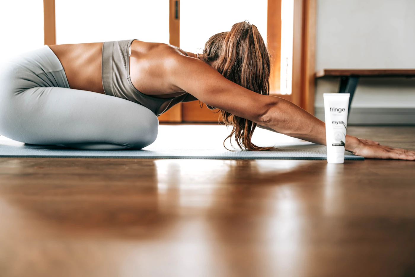 A person practising a traditional Hatha Yoga asana on a wooden floor at home